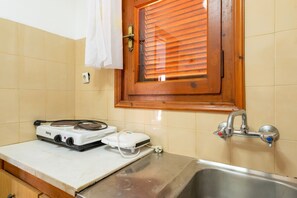 Eine Küche mit Herd, Spüle und einem Fenster mit Holzjalousien.