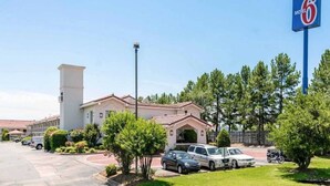 A motel with a parking lot, a sign indicating it's a Motel 6, and a building with a red-tiled roof. - 1 King Bed|Smoking|Micfridge (North Little Rock)