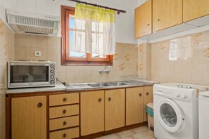 A compact kitchen with a microwave, sink, and washing machine.
