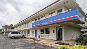 A motel with a 'WELCOME' sign, a parking lot, and a building with multiple windows and balconies. - 2 Full Beds|Smoking,Micfridge (Amherst)
