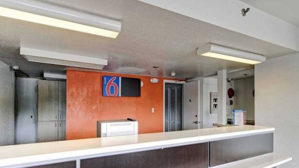 A reception area with a counter, a number 6 sign, and a door. - 2 Full Beds|Smoking,Micfridge (Amherst)