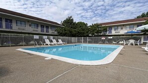 A rectangular pool with a white edge, surrounded by a white fence, and adjacent to a motel with a balcony. - 1 Queen Bed|Non-Smoking (Amherst)