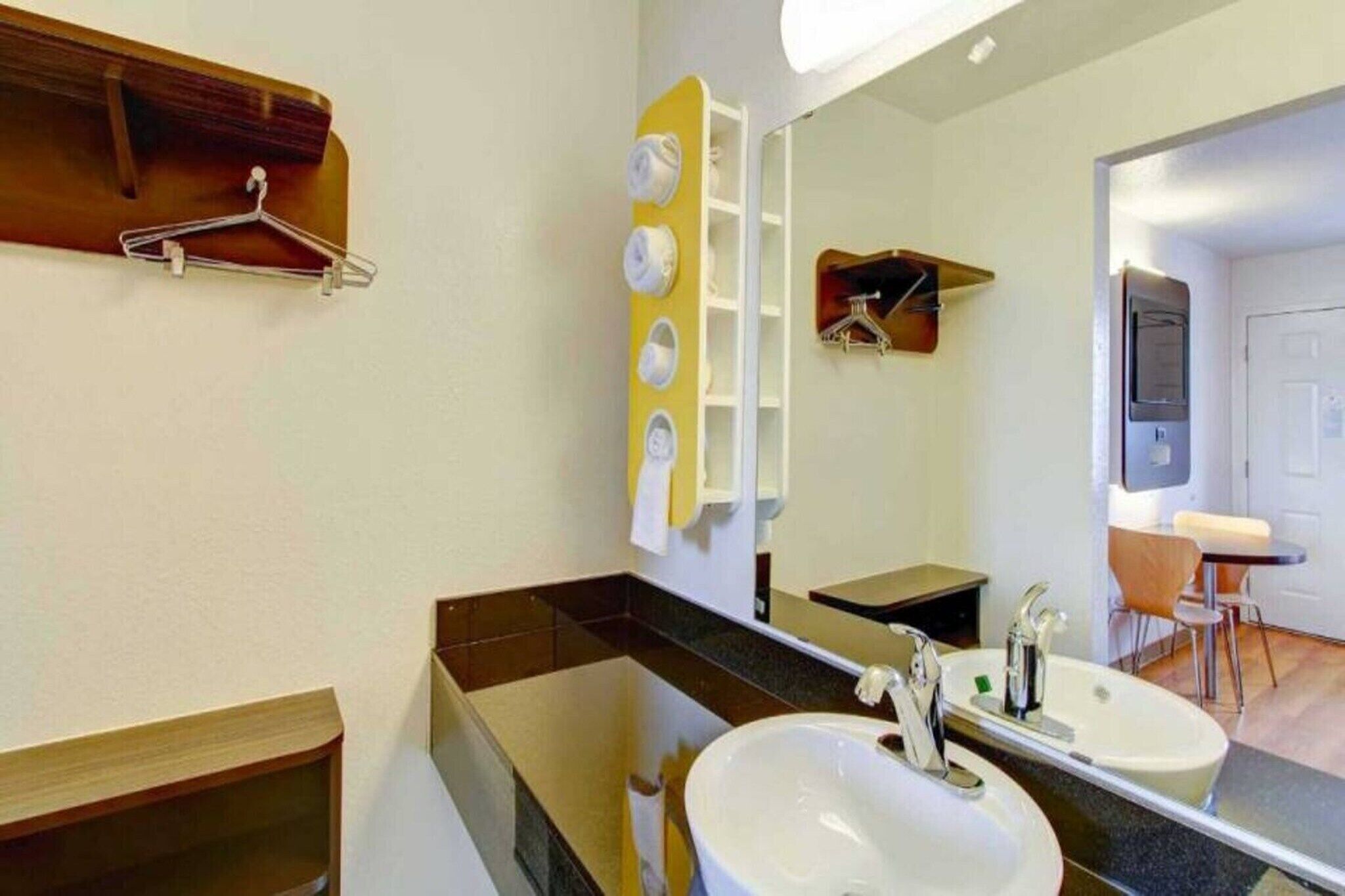 Une salle de bain avec deux lavabos, un miroir, un porte-serviettes et un téléviseur dans un coin.