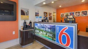 A reception desk with a large sign, a coffee machine, and a security camera.