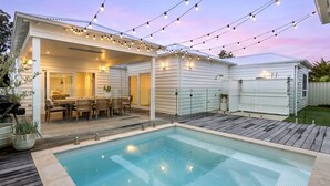 Um quintal com piscina, móveis de pátio e luzes de fada.
