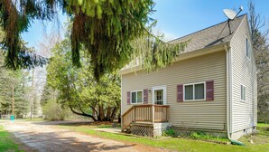 A single-story house with a front porch, a satellite dish, and a driveway leading to the entrance. - 1 Block to Lake Huron Beach! Peaceful Shore House (Fort Gratiot Township)