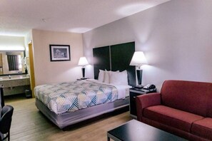 A hotel room with a bed, two bedside lamps, a red sofa, a desk, and a mirror.