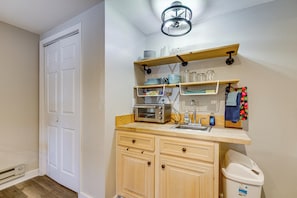 A compact kitchen with wooden cabinets, a built-in microwave, and a sink.