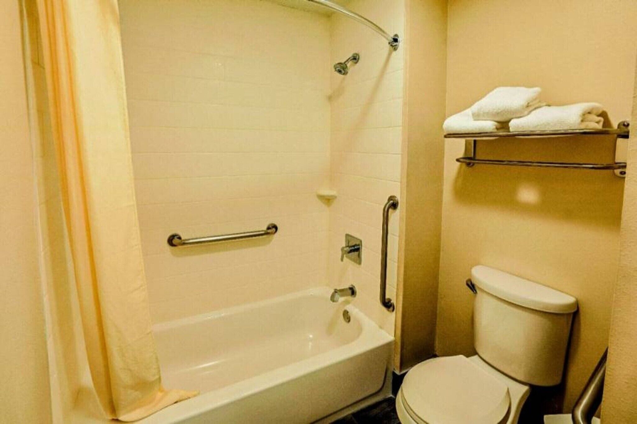 A bathroom with a bathtub, toilet, and towel rack.