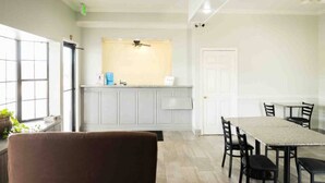 Une cuisine moderne avec des meubles blancs, un coin repas comprenant une table et des chaises, et un ventilateur de plafond.