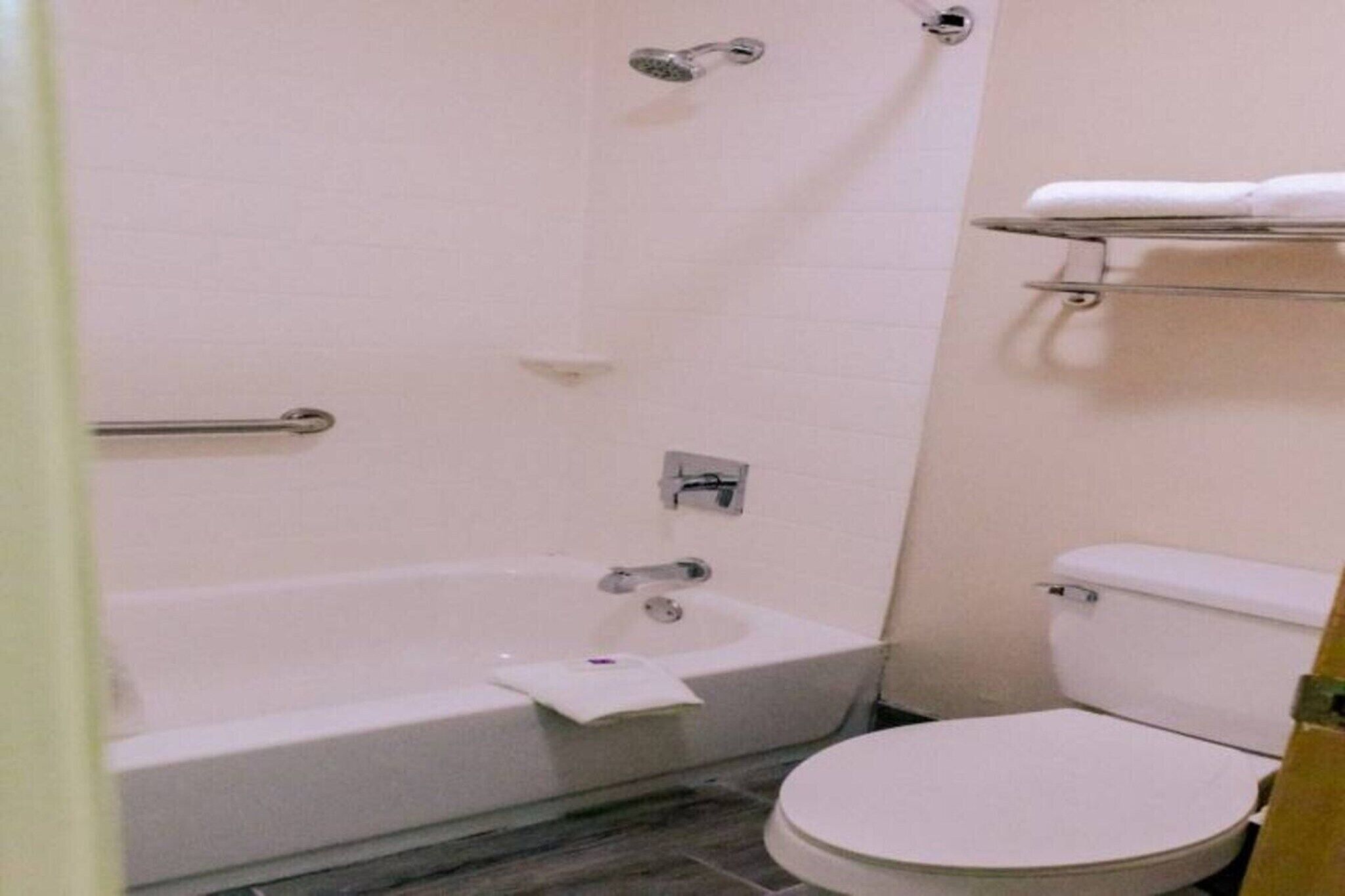 Un baño con bañera, inodoro y un estante con una toalla.
