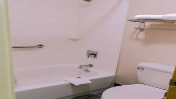 Un baño con bañera, inodoro y un estante con una toalla.