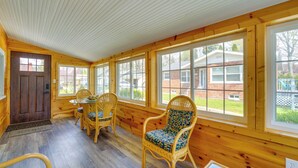 Ein Holzblockhaus-Interieur mit Essbereich, großen Fenstern und einer Tür.
