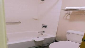 A bathroom with a bathtub, toilet, and a shelf with towels.