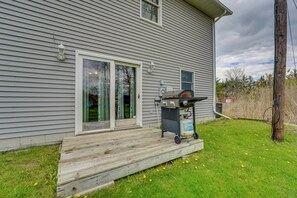 A house with a wooden deck, a barbecue grill, and a gas tank.