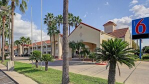 Un motel avec un toit rouge, des palmiers et un ciel d’un bleu éclatant.