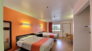 Une chambre d’hôtel avec deux lits, une table à manger et un miroir.