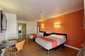 Hotellihuone, jossa on kaksi sänkyä, työpöytä ja tuoli.