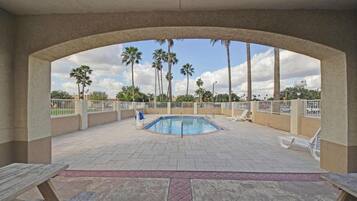 Zona de piscina al aire libre con vista a palmeras y un cielo despejado.