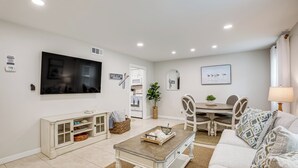 Ein Wohnzimmer mit Fernseher, einem Esstisch mit Stühlen, einer Couch und einem Couchtisch.