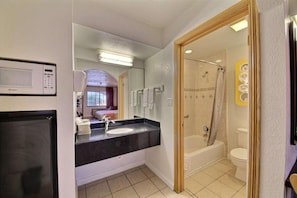 Et badeværelse med vask, spejl, bruser og toilet.