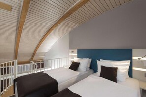 Una habitación con dos camas, techo abovedado y baranda blanca.