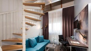 Ein modernes Zimmer mit einer Wendeltreppe, einem blauen Sofa, einem Schreibtisch und einem Stuhl.