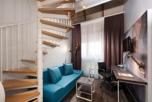 Una habitación moderna con una escalera espiral, un sofá azul, un escritorio y una silla.