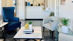 A reception area with a counter, a blue chair, a grey chair, and a coffee table with a plant.