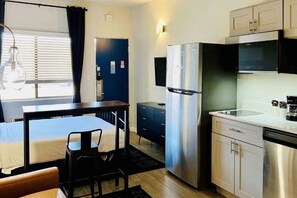 A compact kitchen with a refrigerator, microwave, and sink. There is a small dining area with a table and chairs.