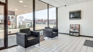 A hotel lobby with large windows, two armchairs, a coffee table, a television, and a magazine rack. - 1 King Bed | Smoking, Kitchen, Sofa-Bed (Longview)