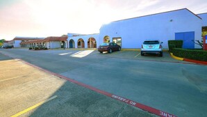 A parking lot with a building featuring arched windows and a flat roof. - 1 King Bed | Smoking, Kitchen, Sofa-Bed (Longview)