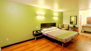 A hotel room with a bed, nightstand, chair, desk, and mirror.