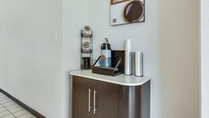 A hotel reception area with a coffee machine, a coffee cup, and a sign that reads 'YOUR MORNING CHARGE UP FOR NO CHARGE.'