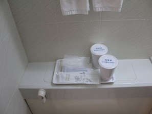 WC-istuin, jossa on paperipyyhkeiden annostelija, WC-paperirulla ja kaksi säiliötä, joissa on merkintä ”STERILOITU”.