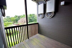 Ein Balkon mit Blick auf Bäume, einem Geländer und zwei an der Wand montierten Klimaanlagen.
