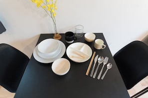 Ein gedeckter Tisch mit Tellern, Schüsseln, einem Glas und Besteck, mit einem Blumenstrauß aus gelben Blumen darauf.
