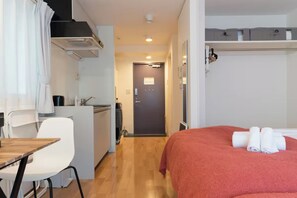 Ein kompaktes Hotelzimmer mit Bett, einer kleinen Küchenzeile, einem Essbereich und einem Badezimmer.