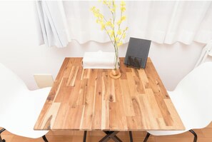 Ein Holztisch mit einer Vase voller gelber Blumen, einem schwarzen Notizbuch und einem weißen Kissen.