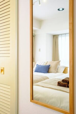 Ein Hotelzimmer mit Bett, Kissen, Decke und einem Spiegel, der den Raum widerspiegelt.