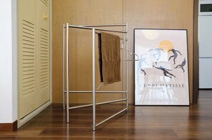 Ein Wäscheständer aus Metall mit einem Handtuch, eine Holztür und ein gerahmtes Kunstwerk an der Wand.