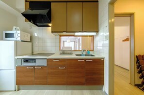 Eine moderne Küche mit Holzschränken, einer Mikrowelle, einem Geschirrspüler und einer Spüle aus Edelstahl.