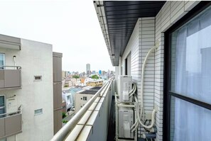 Ein Hochhaus mit Außenklimaanlagen, einem Fenster und Blick auf die Stadtlandschaft.