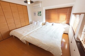 Ein Schlafzimmer mit einem großen Bett, einem Holzschrank und einem Fenster mit Jalousien.