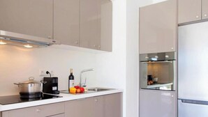 A modern kitchen with a built-in oven, a coffee maker, and a wine bottle on the counter. - Omicron & White Villas (Lefkada)