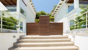 A modern building with a wooden gate, white walls, and a staircase leading to the entrance. - Omicron & White Villas (Lefkada)