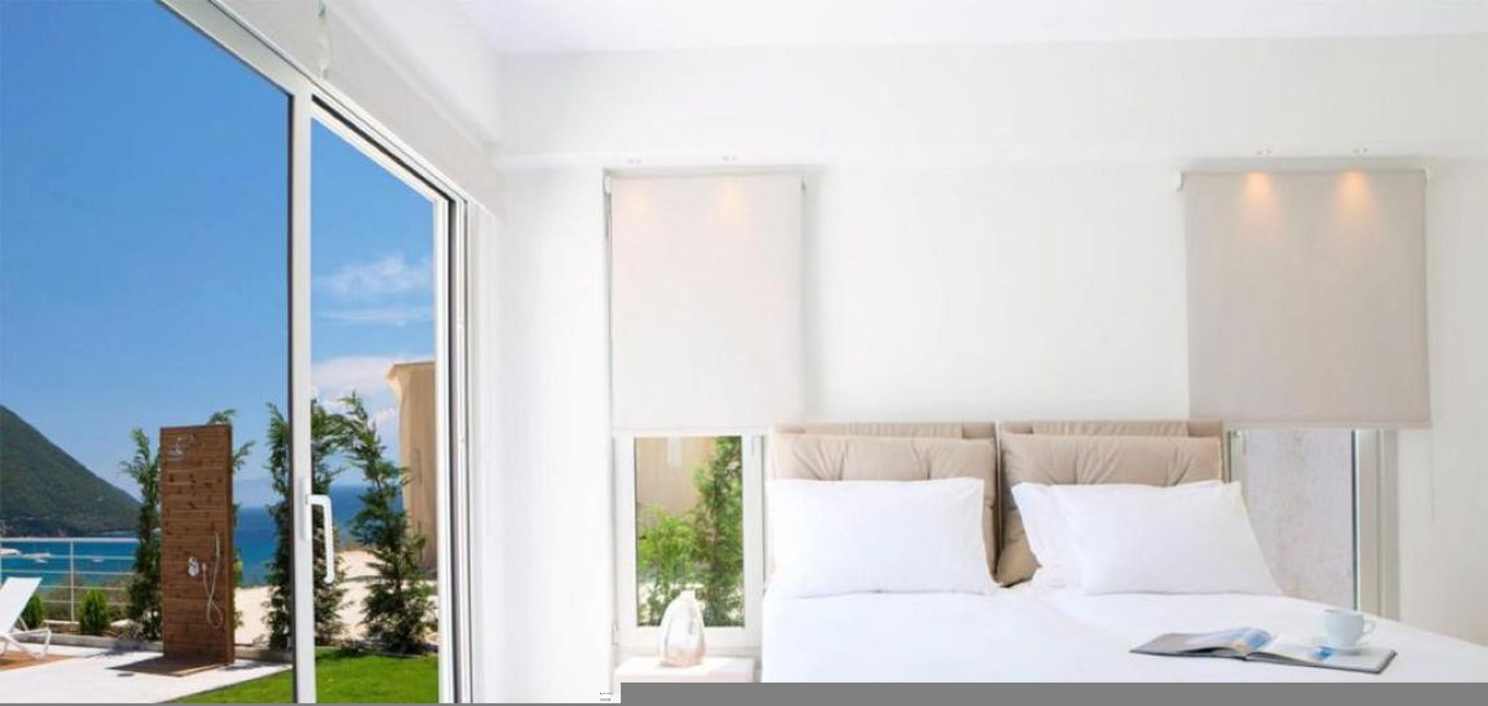 A modern hotel room with a large bed, a view of the ocean, and a sliding glass door leading to a balcony.