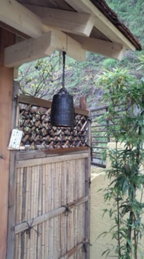 A bamboo fence with a hanging bell and a small white sign.