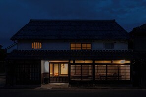 A traditional Japanese house with a tiled roof, wooden sliding doors, and a small porch.