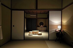 Et traditionelt japansk rum med tatamimåtter, et lavt bord med lampe og en skydedør.